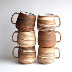 four coffee cups stacked on top of each other in different shapes and sizes, all made out of wood