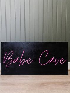 a black sign with pink writing on it that says barbie cave in cursive font