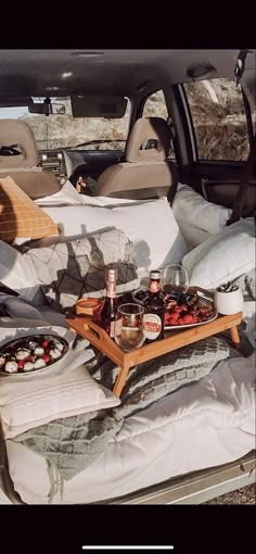 an open car trunk with food and drinks on the trays in front of it