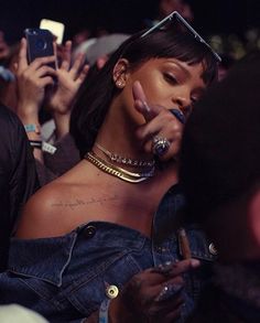 a woman with her finger in her mouth and other people holding their cell phones up to her face