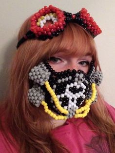 a woman with red hair wearing a beaded mask