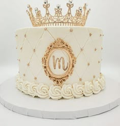 a white cake with gold decorations and a crown on top