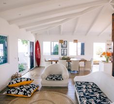 a living room filled with white furniture and lots of windows on top of the walls