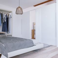 a bedroom with a bed, closet and clothes hanging on the rack in it's corner