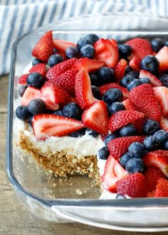 a dessert with strawberries and blueberries on top in a glass dish, ready to be eaten