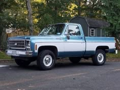 a blue and white truck parked in front of a house