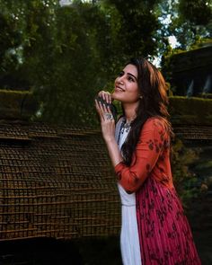 a woman in a red and white dress standing next to a bird cage with her hands together