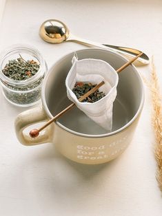 a cup filled with tea next to two spoons