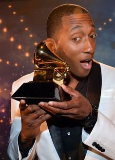 a man holding an award in his right hand and making a surprised face at the camera