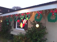 a house decorated for christmas with lights and decorations on the front porch, along with garlands