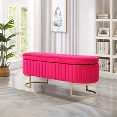 a pink bench sitting on top of a hard wood floor next to a potted plant