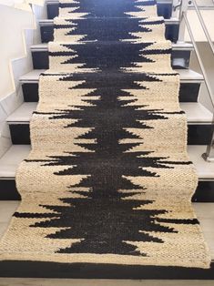 a carpeted stair runner with black and white designs on the bottom, next to some stairs