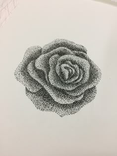 a black and white photo of a rose made out of small dots on the side of a piece of paper