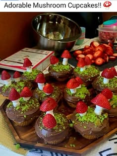 chocolate cupcakes topped with strawberries and green sprinkles on a wooden tray