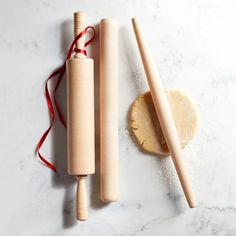 two wooden rolling pins next to a doughnut on a marble surface with red string