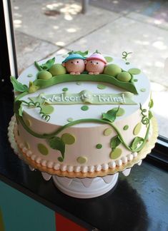 a cake with two people sitting on top of it in front of a glass window