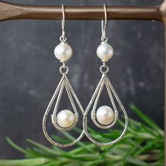 Freshwater pearl and sterling silver earrings in a lovely long teardrop shape. These elegant dangle earrings would be perfect for occasion wear or even striking bridal jewellery.  This unusual double teardrop design features a mix of smooth and hammered textured wire and a central wire wrapped pearl, all hung from a handmade ear hook for a beautiful artisan finish. A contemporary take on classic pearl earrings. 🤍 MATERIALS .925 Sterling Silver Freshwater pearl (ivory tone) 🤍 UNIQUE This piece includes beautiful quality freshwater pearls which by nature vary in their shape and size. Please expect slight variation from the photo as each piece is handmade to order. 🤍 SIZE Approximately 2.5 inches long. 🤍 GIFT Gift wrapping included - presented in a Lillibets Millinery branded box, wrapped Classic Pearl Earrings, Freshwater Pearl Drop Earrings, Teardrop Dangle Earrings, West Yorkshire, Long Dangle Earrings, Sterling Silver Dangle Earrings, Pearl Earrings Dangle, Silver Earrings Dangle, Etsy Earrings Dangle