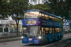 a double decker bus is driving down the street in front of some buildings and trees