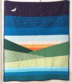 a quilted wall hanging on the side of a door with mountains and stars in the sky