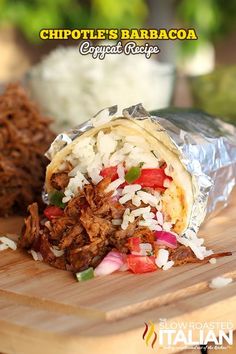 a close up of a burrito on a cutting board with shredded meat and vegetables