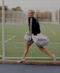 a woman running across a soccer field with her foot in the air and one hand on her hip