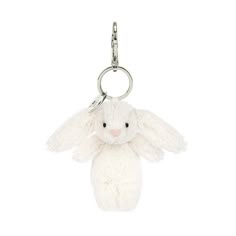 a white stuffed animal keychain hanging from a metal hook on a white background