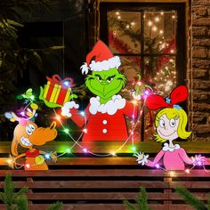 the grinch family with christmas lights in front of a house