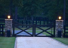 a gate with two lights at the top and an entrance way leading to a driveway