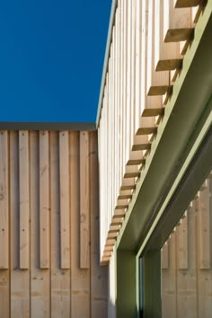 the side of a building with wooden slats on it's sides and a blue sky in the background