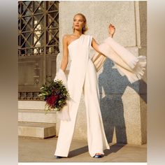 a woman standing in front of a building wearing white