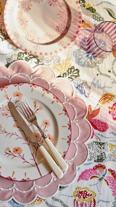 a plate with two forks on top of it next to a fork and knife sitting on a floral table cloth