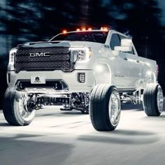 a white truck driving down a street at night with lights on it's headlights