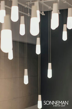 a group of lights hanging from the ceiling in a room with black walls and flooring