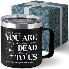 a black and silver coffee mug next to a blue gift box with the words you are dead to us on it