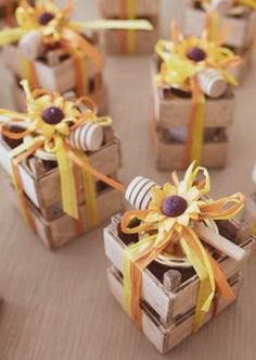 small wooden boxes with candy wrapped in yellow and orange ribbons on top of a table