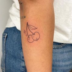 a woman with a tattoo on her arm holding a banana and cherries in one hand