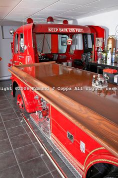 a red fire truck sitting on top of a wooden counter next to a bar in a room