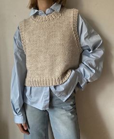 a doll wearing a sweater and jeans is standing in front of a wall with her hands on her hips