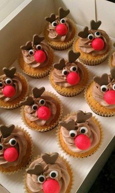 cupcakes with frosting and reindeer noses are displayed in a box on a table