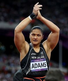 a woman holding her hands in the air while standing on top of a race track