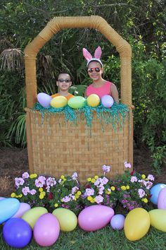 two people wearing bunny ears in a basket filled with eggs