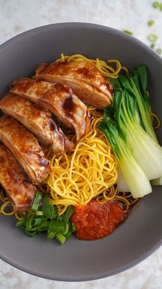 a bowl filled with noodles, meat and veggies on top of a table