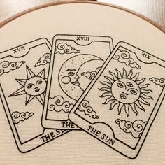 three tarot cards with the sun and moon on them are embroidered onto a piece of fabric