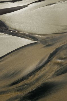 an aerial view of the sand and water at low tide beach, with small waves coming in