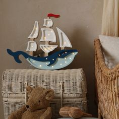 a teddy bear sitting next to a basket with a sailboat on it