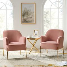 two pink chairs sitting next to each other on top of a rug in front of windows