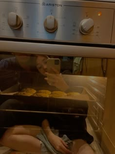 a woman taking a photo of some food in an oven