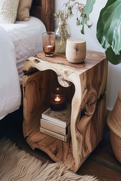 a wooden table with a candle and some books on it next to a potted plant