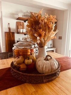 a basket filled with pumpkins and gourds on top of a wooden table