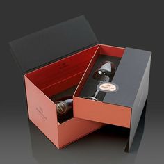 an open red box with a wine bottle in it on a black surface and the lid opened